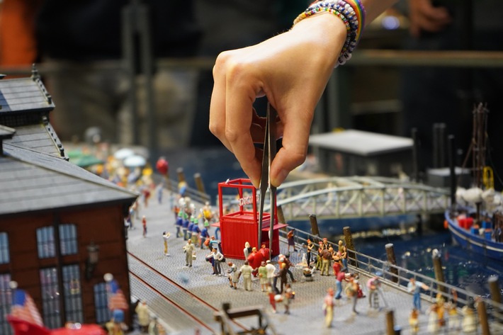 Bild zeigt Hand, die Figuren in die Miniaturlandschaft stellt.